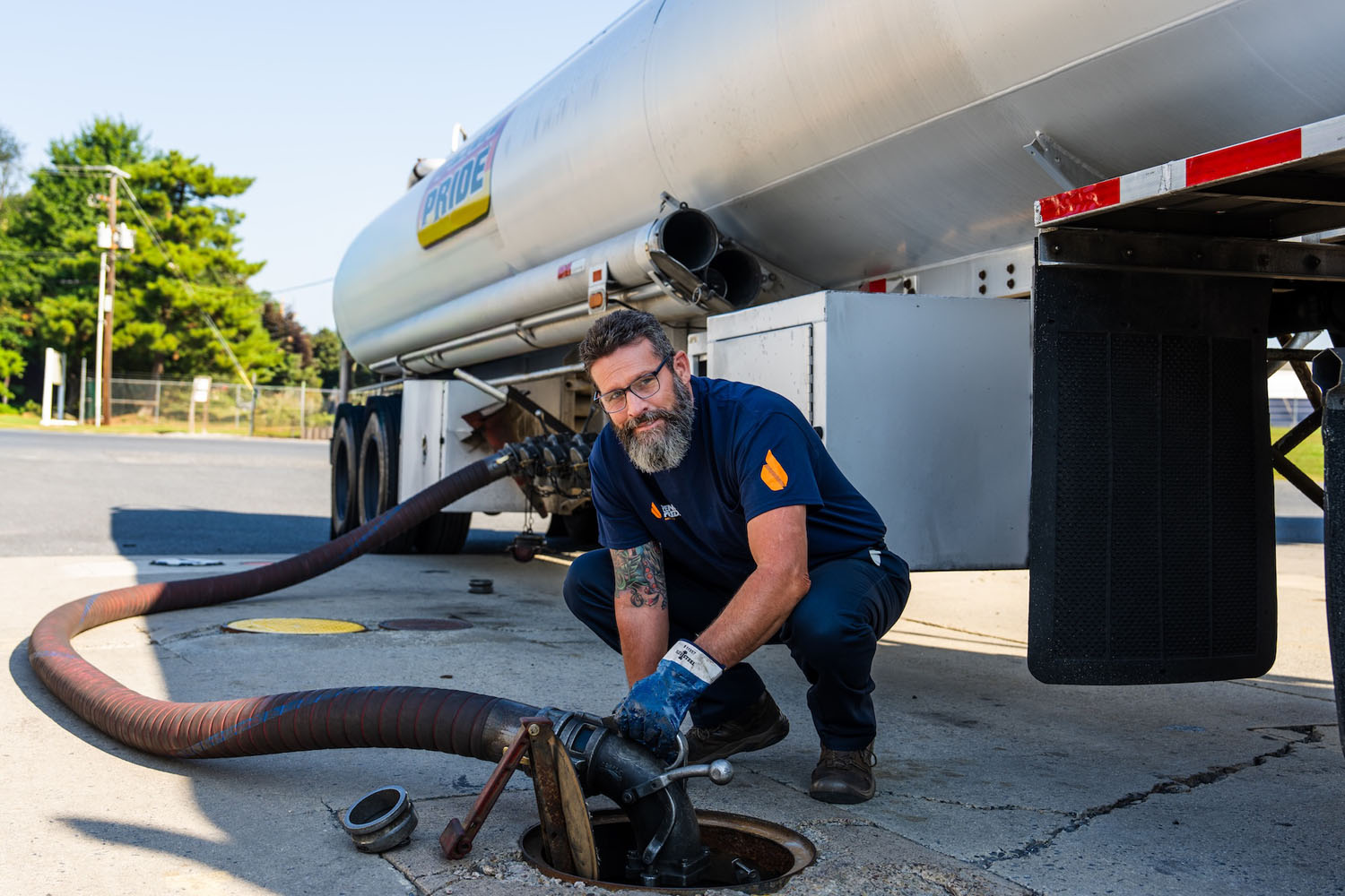 employee filling tank with fuel truck in the background