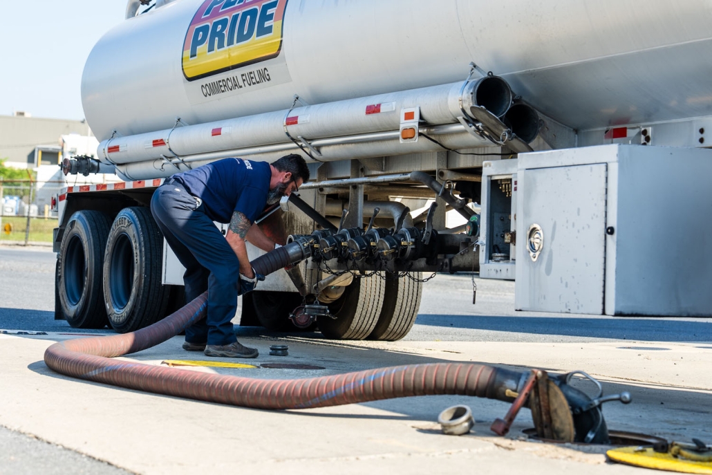 employee filling fuel tank at a gas station while adjusting the hose