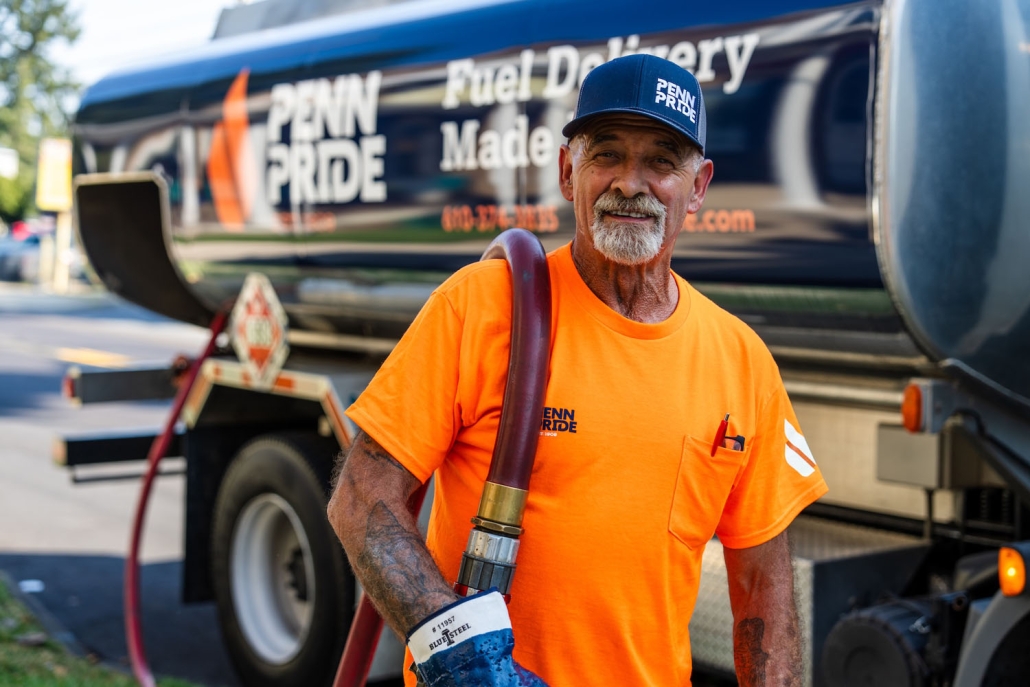 happy employee pulling hose with fuel truck in the background