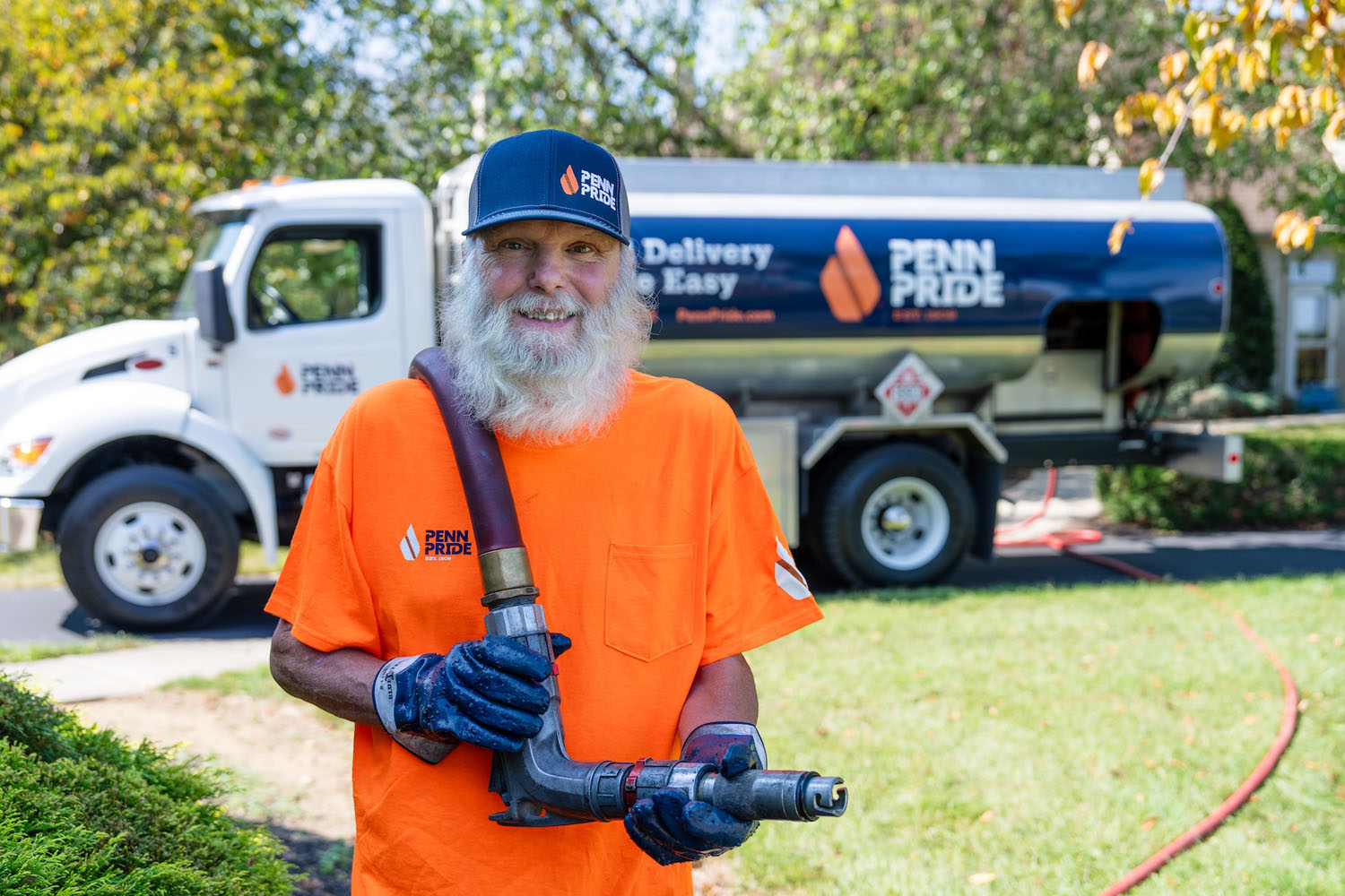 happy employee holding hose with fuel truck in the background