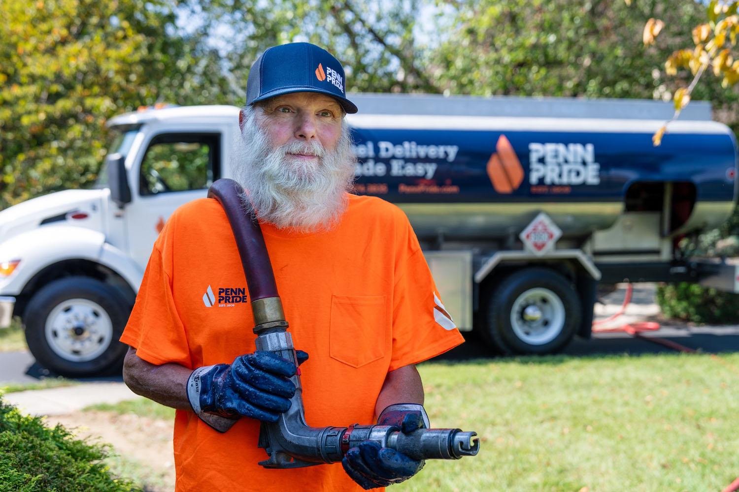 employee pulling hose with fuel truck in the background