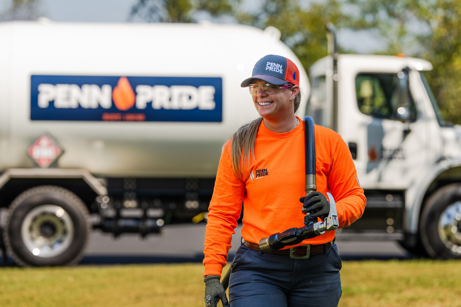 employee pulling hose with propane truck in the background