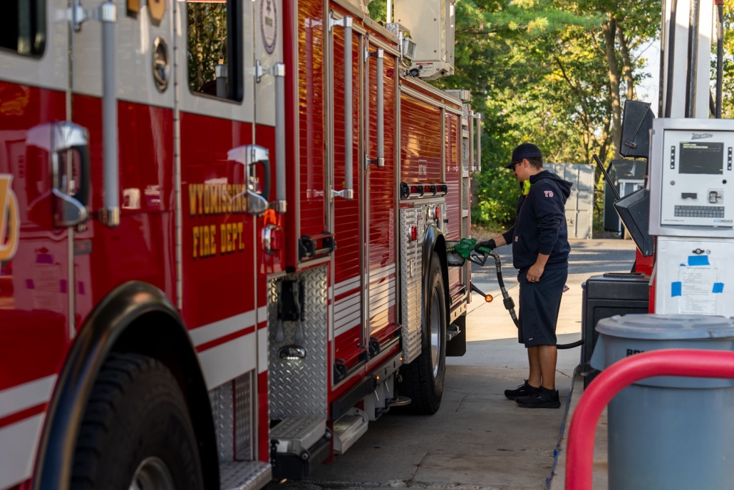 man filling up a firetruck at a gas station